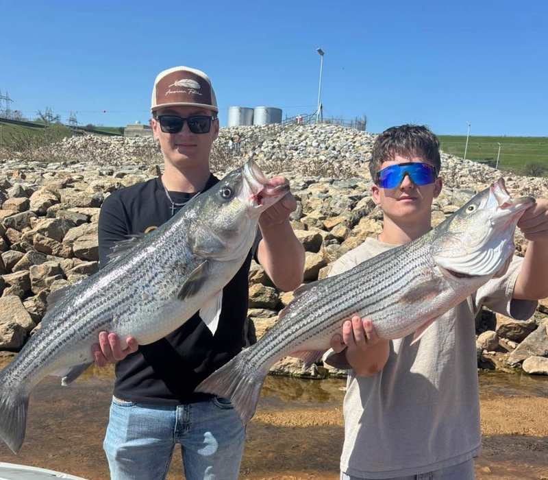 fishing-report-march-2026-lake-texoma-FI Two anglers holding large striped bass near Denison Dam rocks Lake Texoma guided fishing