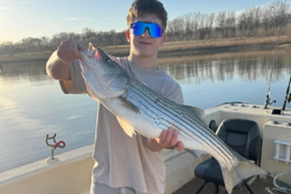 lake-texoma-fishing-report-march-2026-b Teen angler holding striped bass on boat during Lake Texoma guided fishing trip